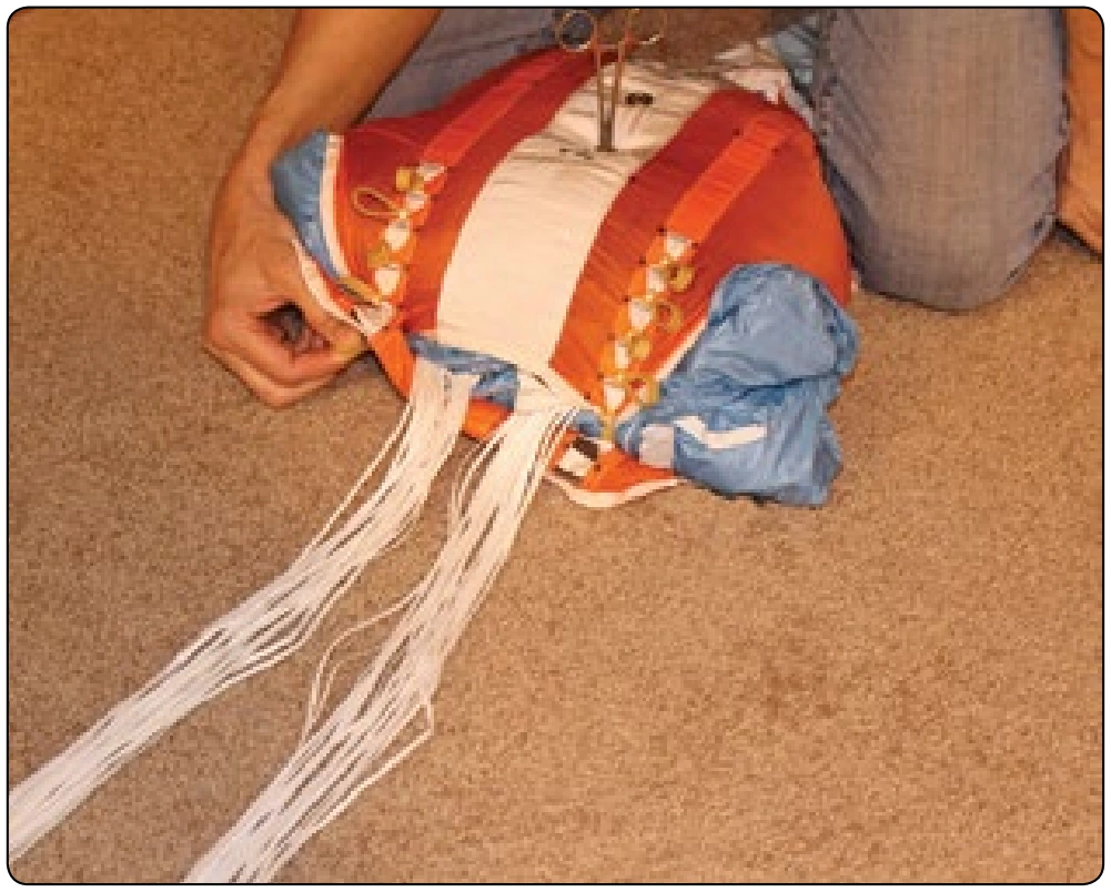 Figure 5-138. Use the flaps of the bag to control the canopy and help push it into the bag.