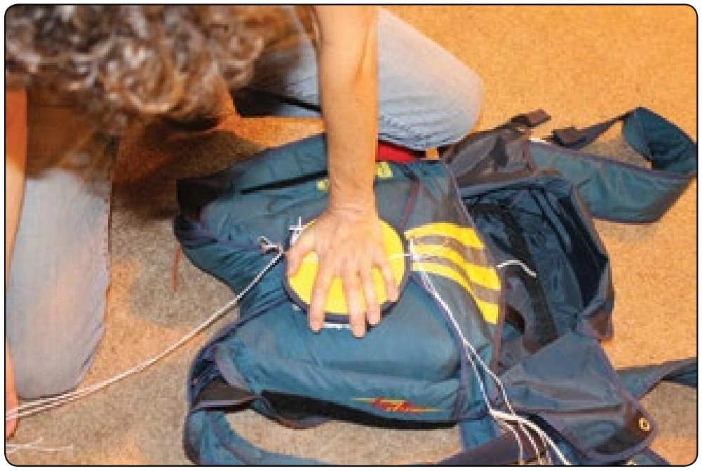 Figure 5-158. Compress pilot chute tucking fabric and mesh between the coils of the spring.